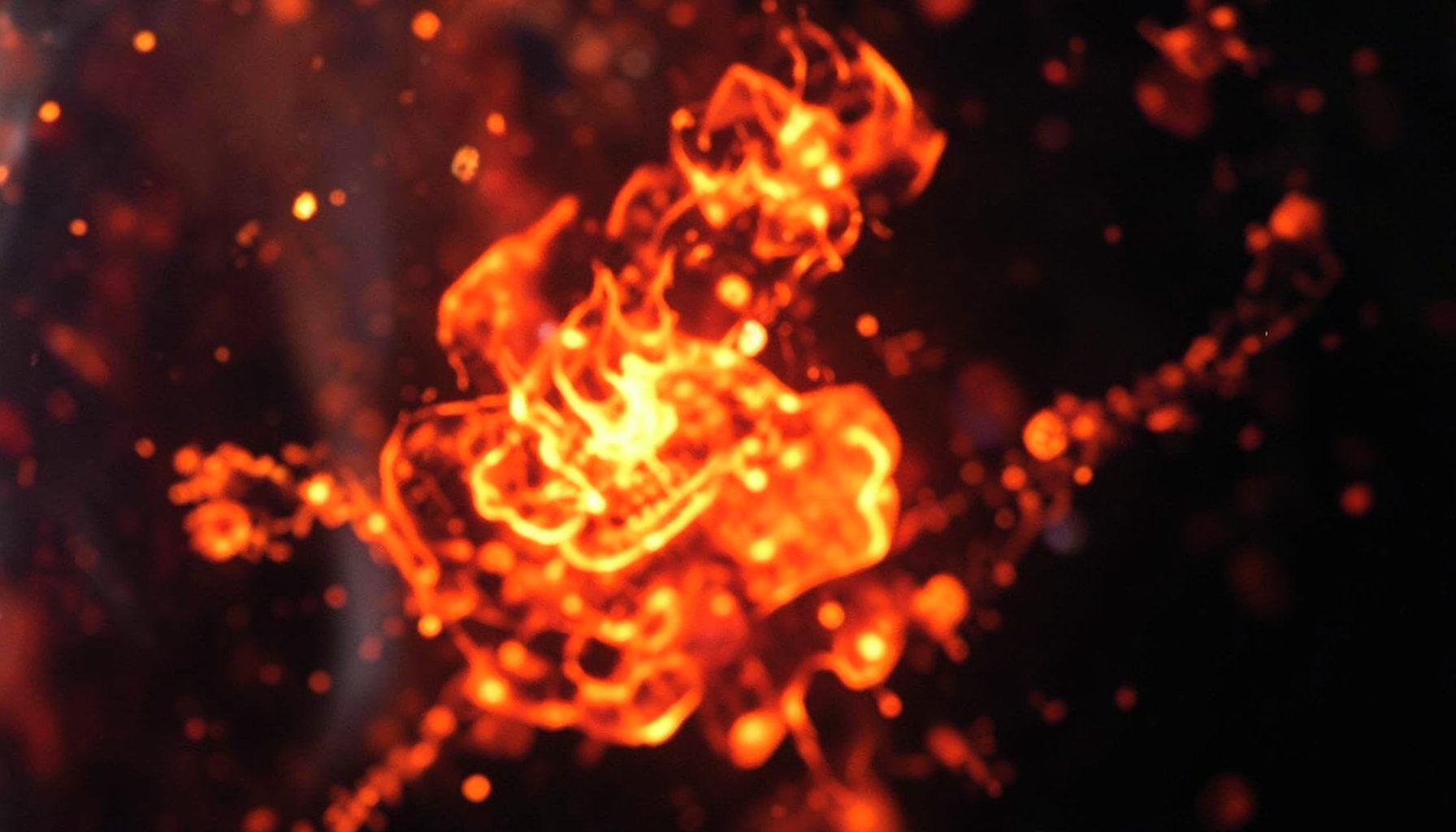 A fiery, warm-toned image of molten orange and crimson embers swirling against a dark backdrop, conveying intensity and transformation.