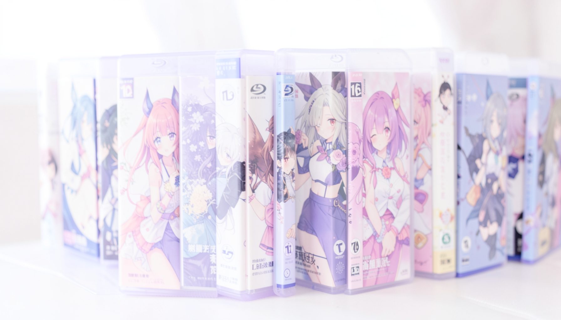 A softly lit photograph of anime Blu-ray cases lined up, pale lavender and white tones